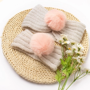 Matching beige knit headband set with pink pom-poms for mother and child on woven mat