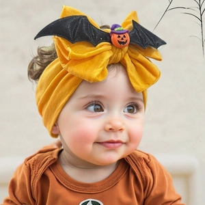 Detail of baby Halloween headband with yellow bow, glitter bat wings and pumpkin