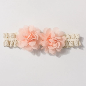 Detailed close-up of cream lace headband with two soft peach chiffon flower decorations