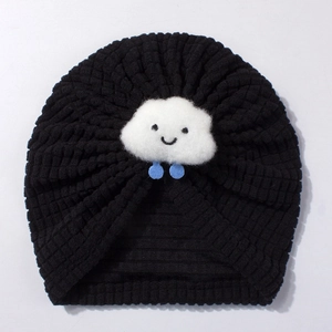 Detailed close-up of a black knit baby turban hat with a smiling white cloud decoration
