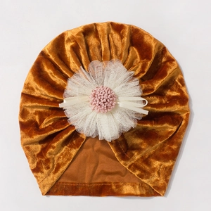 Detail of caramel velvet baby hat with large white lace flower and pink stamen decoration