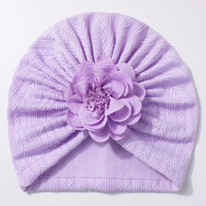 Gros plan du bonnet turban bébé violet clair avec tricot texturé et grande fleur en tissu