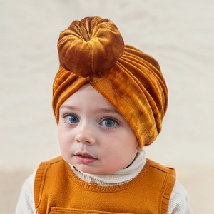 Close-up of ginger yellow baby velvet turban hat with donut knot on cute infant