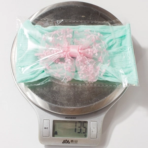 Détail montrant le bandeau pour bébé pesant 13,5 g sur une balance de précision