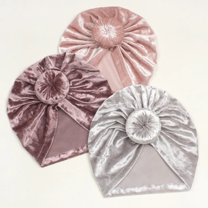 Flat lay of velvet baby turban hats with donut knots in pink, purple and silver grey