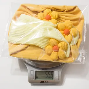 Detail shot of newborn hat and socks set in yellow weighing 55.6g in packaging