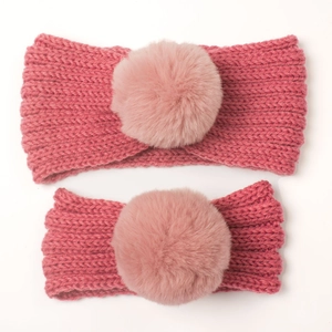 Detail view of pink knit headband set with oversized soft faux fur pom-poms for winter