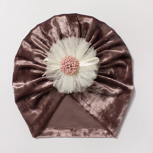 Macro detail of brown velvet baby hat featuring a layered white mesh flower and pink center