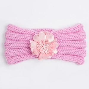 Detailed close-up of pink knitted baby headband featuring a soft decorative fabric flower