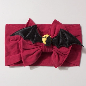 Halloween baby headband with red knit bow and black bat wings over a haunted castle