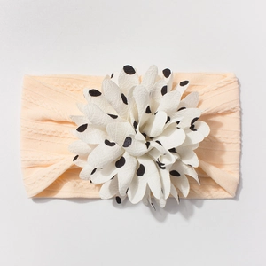 Detailed macro view of baby headband with white polka dot flower and pink ribbed fabric
