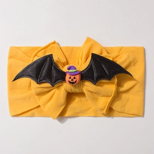 Detailed view of yellow nylon headband with bow, bat wings and small pumpkin doll