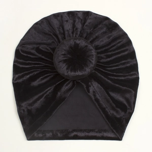 Detail of black velvet baby turban hat featuring pleated texture and bun decoration