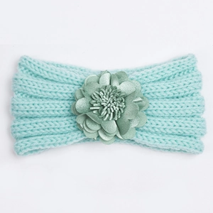 Detail of mint green knitted baby headband with a large layered 3D floral decoration