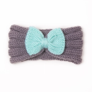 Dettaglio di fascia in maglia per neonati con filato grigio-viola e fiocco verde menta