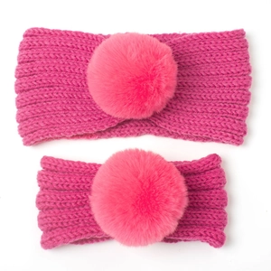 Detail of rose pink cable knit parent-child headband set with large matching faux fur pompoms