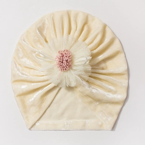 Detail of soft cream velvet baby hat with a large white lace flower and pink center