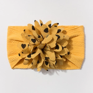 Detailed close-up of yellow jacquard nylon baby headband with large heart print floral bow
