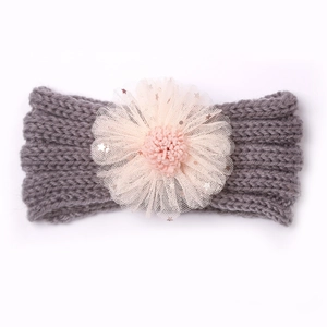 Détail d'un bandeau en tricot gris pour bébé avec fleur en tulle rose et paillettes
