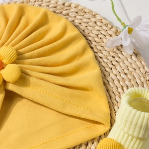 Detail of yellow knit cotton baby turban hat with a large rib fabric floral accent