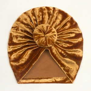 Detailed view of golden velvet turban baby hat with a pleated donut knot and soft texture