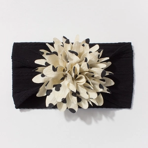 Close-up of baby nylon headband with large cream polka dot flower and black elastic band