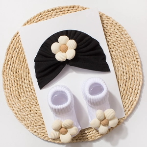 Detail of baby turban and socks set with 3D daisy flower decorations on white card