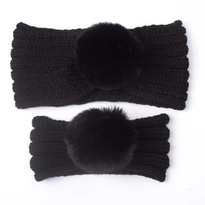 Detail of parent-child black knitted headbands with large fluffy faux fur pom-poms