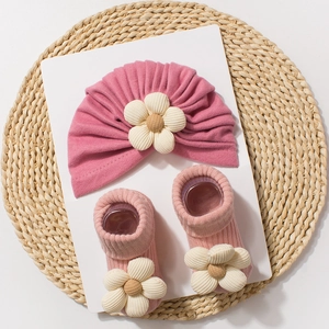 Detailed view of baby floral headband and ribbed socks set on a natural straw mat