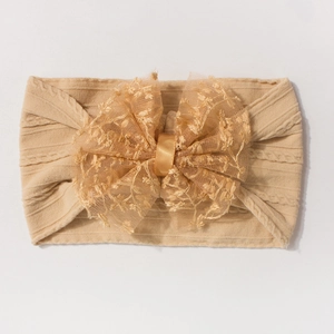 Détail du bandeau bébé en tricot extensible avec un grand nœud en dentelle et tulle