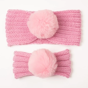 Detailed knit texture of pink parent-child headbands with faux fur pom pom decoration
