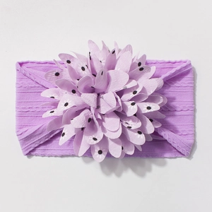 Detail of baby elastic headband featuring a large purple chiffon floral bow with polka dots