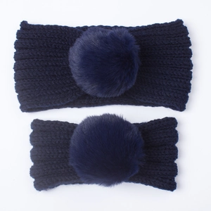 Navy blue knitted headband set with large faux fur pom-poms for winter warmth