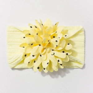 Detail of baby headband featuring yellow jacquard nylon and a large black polka dot floral bow