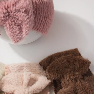 Close-up of soft plush baby headbands with bow in pink, brown, and beige colors