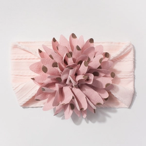 Close-up of pink elastic baby headband with textured knit fabric and polka dot floral detail