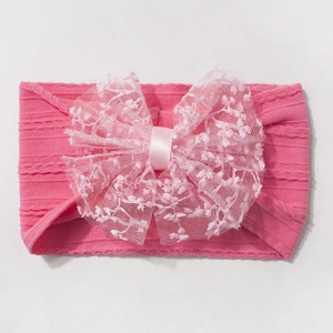 Gros plan d'un bandeau rose pour bébé en nylon jacquard avec un grand nœud en dentelle