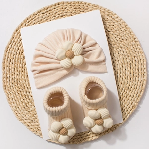 Baby beige knit hat and socks set with 3D polka dot flower design on woven mat