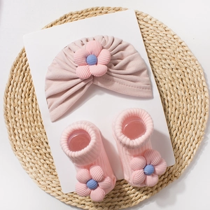 Detail of pink ribbed knit baby hat and socks set featuring 3D floral decorations