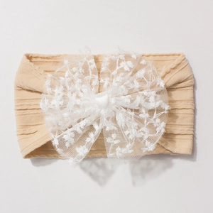 Détail du bandeau côtelé pour bébé avec un grand nœud en dentelle florale blanche