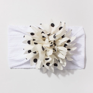 Detail of baby headband featuring white knitted texture and black polka dot floral decor