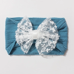 Détail du bandeau bébé avec ruban côtelé sarcelle et grand nœud en dentelle blanche
