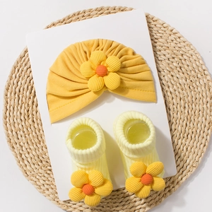 Detailed macro view of yellow knitted baby turban hat and matching socks with sunflower