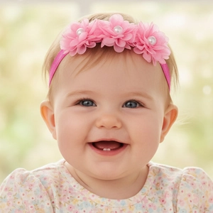 Détail de fleurs en mousseline rose et perles sur un bandeau élastique pour nouveau-né