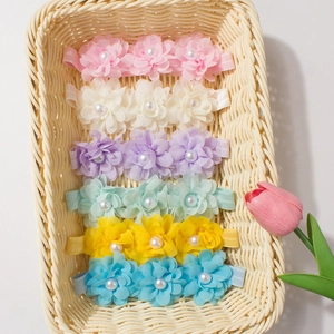 Détail de six bandeaux bébé avec fleurs en mousseline et perles dans un panier