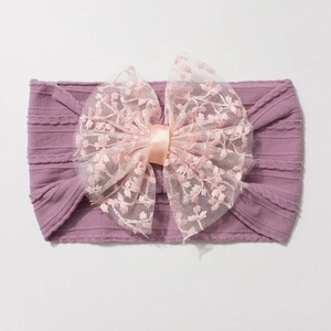 Détail d'un bandeau mauve pour bébé avec grand nœud en dentelle et maille torsadée douce