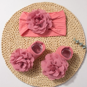 Infant gift set featuring a pink floral headband and matching socks on a woven mat