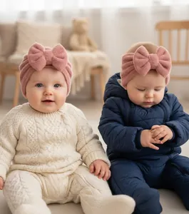 Close-up of pink knit baby headband and hat set with large decorative bows for infant warmth