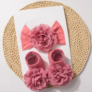 Close-up of pink baby headband and floral socks set on a natural woven mat