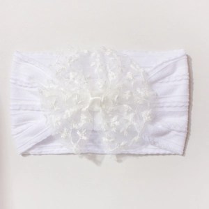 Gros plan d'un bandeau en dentelle blanche pour bébé avec texture tricotée et nœud